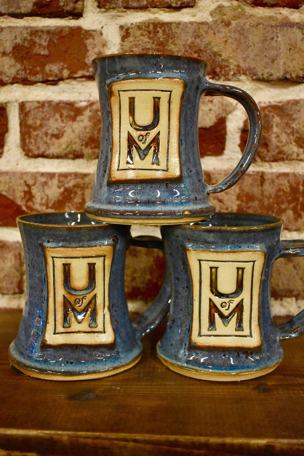 A set of U of M mugs created at The \Belltower Artisans+